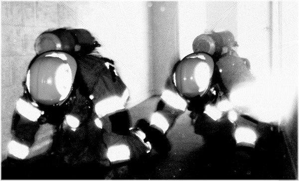 two firefighters crawling in hallway, heads down